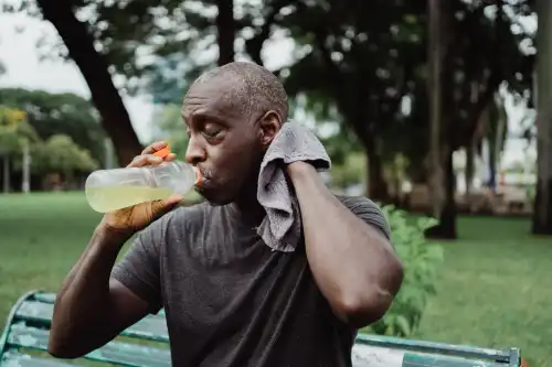 Senior drinking water and wiping sweat